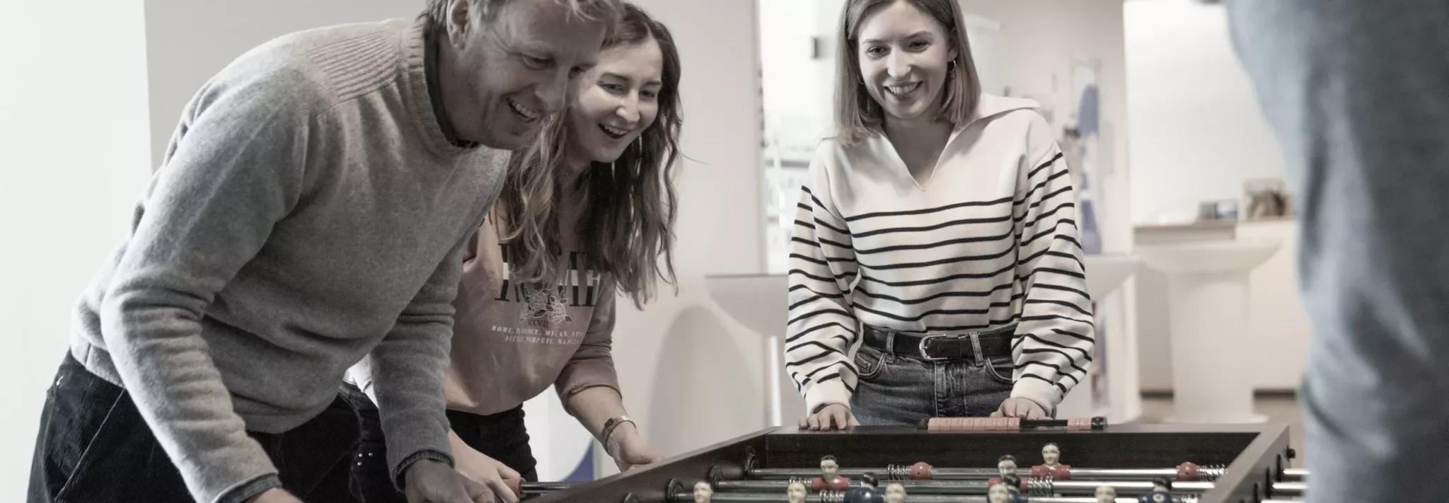 Drei Mitarbeiter aus dem Marketing-Agentur-Team, die Tischkicker spielen