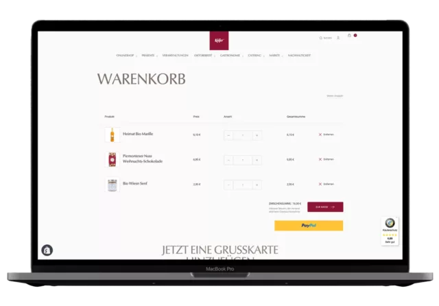 On a laptop screen, the shopping cart from the Shopify online store is displayed in German, showing the item quantities and a "Pay" button.
