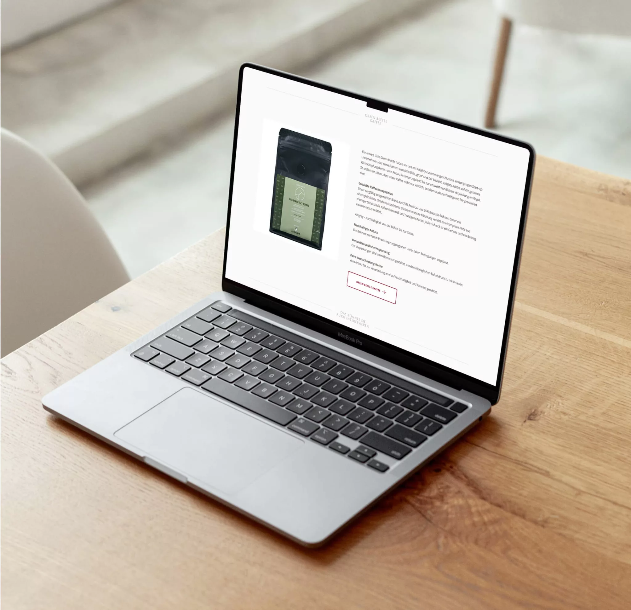 Ein Laptop auf einem Holztisch zeigt eine Produktseite des Feinkost Käfer Online Shopf mit einer Kaffeetüte mit beschreibendem Text und einem Button "In den Warenkorb".