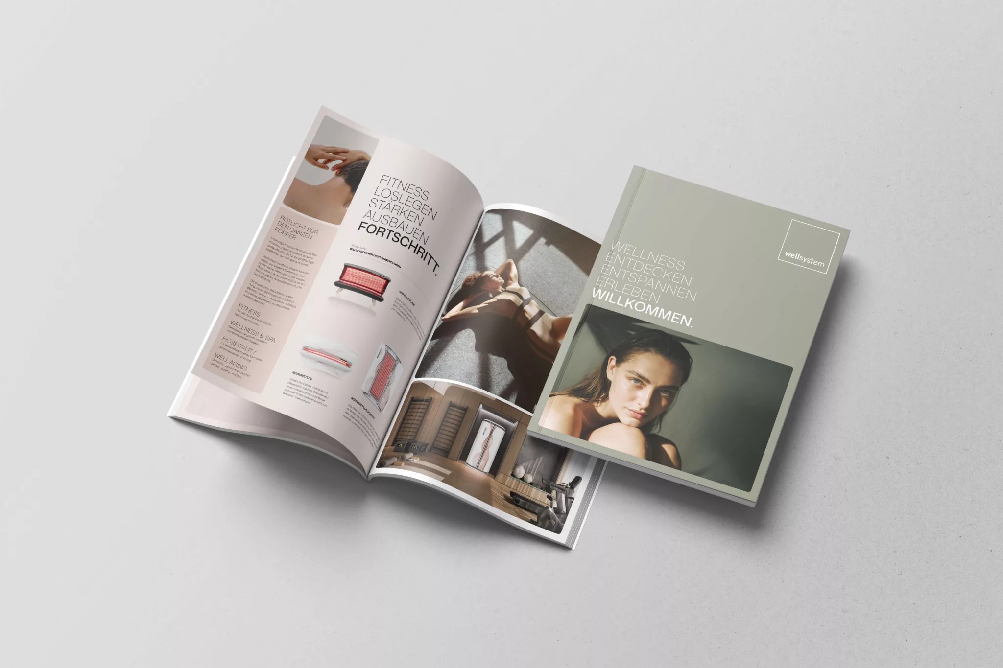 Ein aufgeschlagenes Magazin von wellsystem neben einem geschlossenen Exemplar mit einem Frauenporträt und der Headline "Wellness. Entdecken. Entspannen. Erleben. Willkommen."